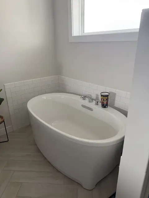 Clean white freestanding bathtub with white subway tile