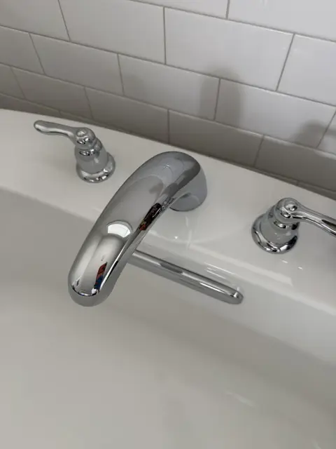Close-up of a polished chrome bathtub faucet and handles