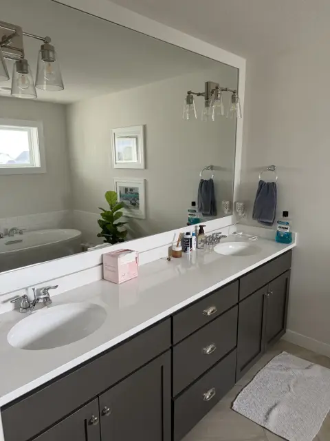 Clean double vanity with white countertop, dark cabinets and a streak-free mirror