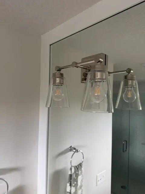 Clean bathroom mirror and three-light vanity fixture