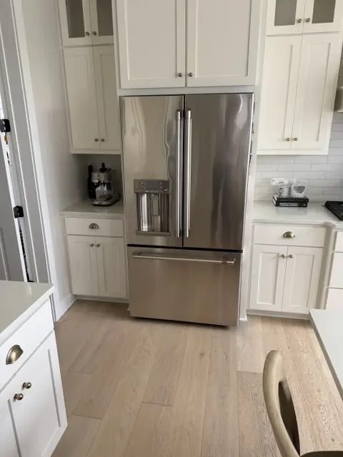 Stainless steel refrigerator and white cabinets wiped clean