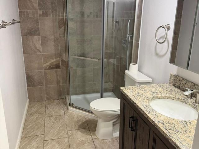 Clean bathroom with tiled shower, vanity and floor