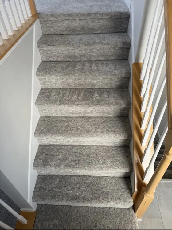 Gray carpeted staircase after cleaning at Diane T.'s home, with fresh cleaning wand marks on the steps